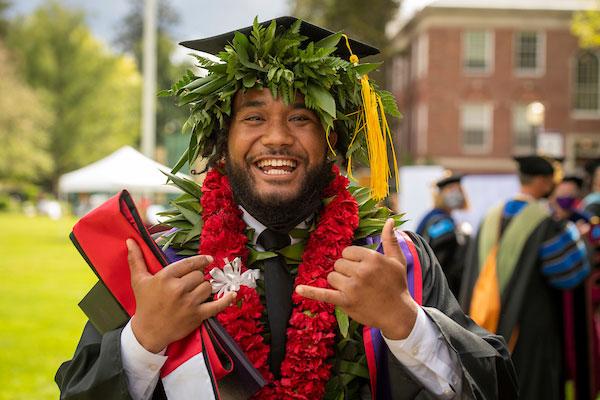 Male student in cap, gown and cords at Commencement.